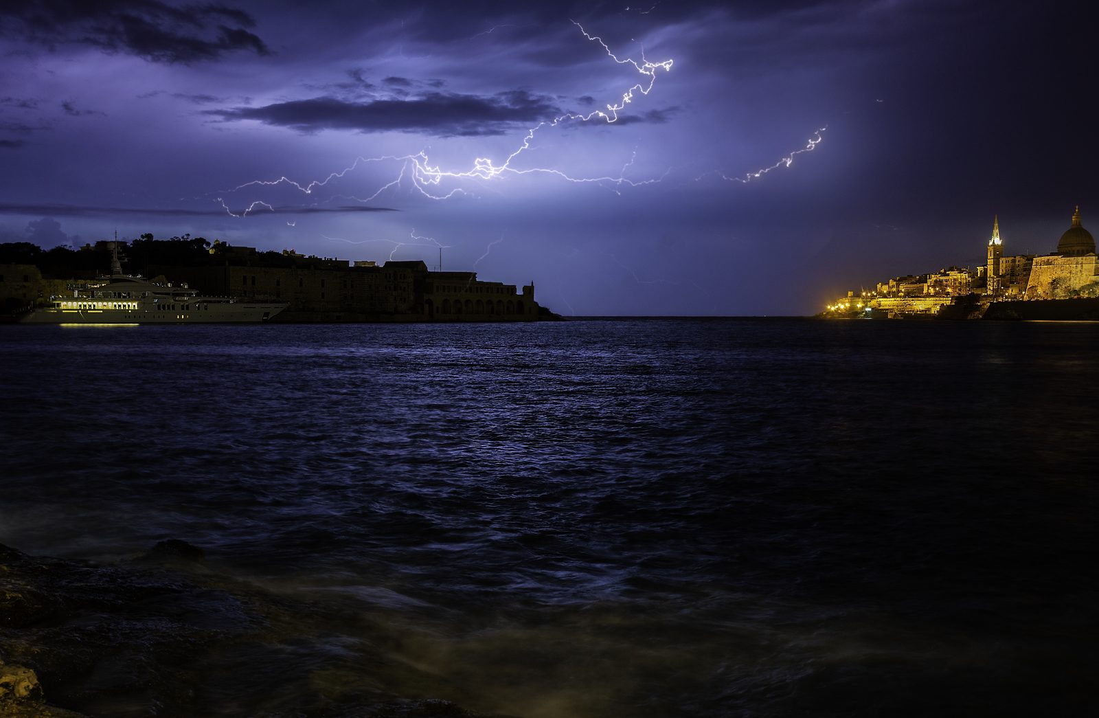 A lightning crawler crossing the sky above the Grand Harbour and Valletta at night